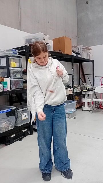 Student in cream hoodie and jeans working with clay in a bright studio workshop