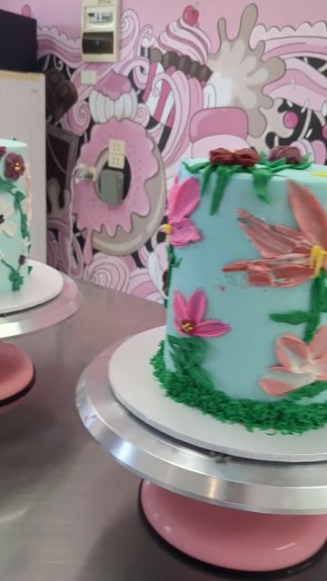 Decorated cake with colorful piped flowers on a rotating turntable in a studio space.