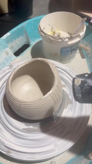 Finished ceramic bowls with white glaze on a turquoise work tray.