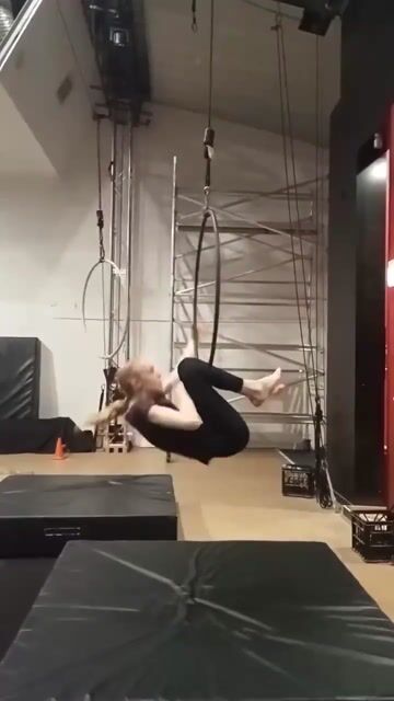 Aerial yoga student suspended in fabric sling performing an inversion pose